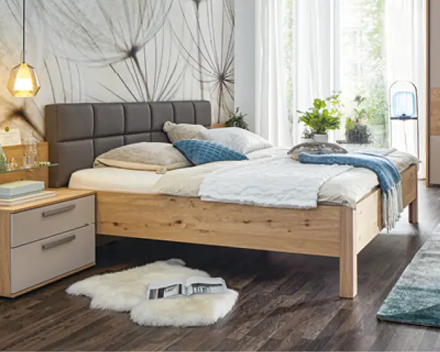 Modernes Schlafzimmer mit Massivholzbett, gepolstertem Kopfteil, Nachttisch und natürlichem Holzboden. Hochwertige Schlafzimmermöbel mit warmen Farben, klaren Linien und wohnlicher Atmosphäre für erholsamen Schlaf.